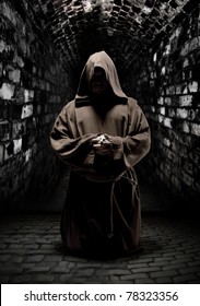 Mystery monk praying on kneels in dark temple corridor