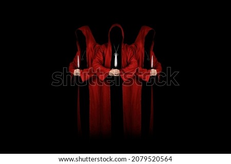 Mystery people in a red hooded cloaks in the dark holding ritual daggers. Hiding face in shadow.  Satanic symbols. Dark ritual. Sectarians. Isolated on black.