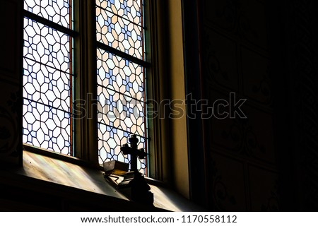 Mystic cross in the shadow in front of the stained transparent glass in a  gothic catholic cathedral