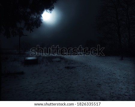 Mystical abandoned cemetery at night. Large bright moon over the night cemetery in winter with fog.