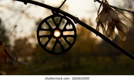
Mystical background, view of the sun at sunset through a pagan solar amulet hanging on a tree branch in the forest in autumn		