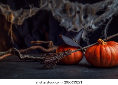 Mystical background of a witch. A decorative Halloween photo with a hat, pumpkins, spider webs and a broom. Background in black and orange colors close-up.  - Powered by Shutterstock
