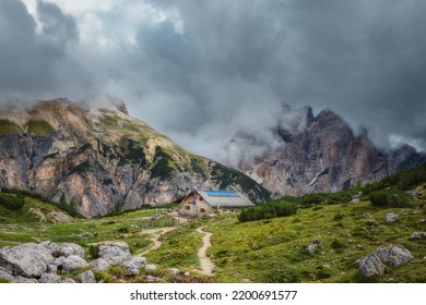 Mystical Beautiful Landscape With Rocky Mountains And Beautiful Mountain House In The Fog In Cloudy Weather, Italian Alps. Tre Cime Park In Dolomites, Italy