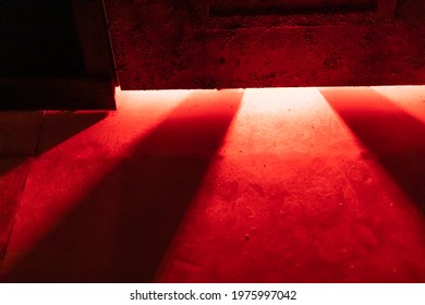 A mystical and dangerous red light through a gap under the door. Fabulous atmosphere of mysteries and horrors for decor