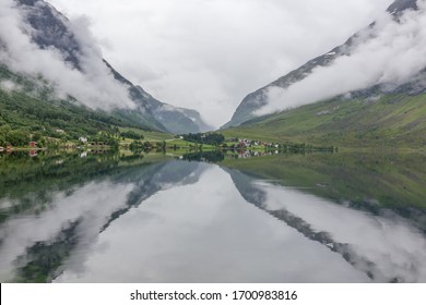 A mystical fjord with dark clouds in Norway with mountains and fog hanging over the water in a beautiful monochrome blue color. selective focus