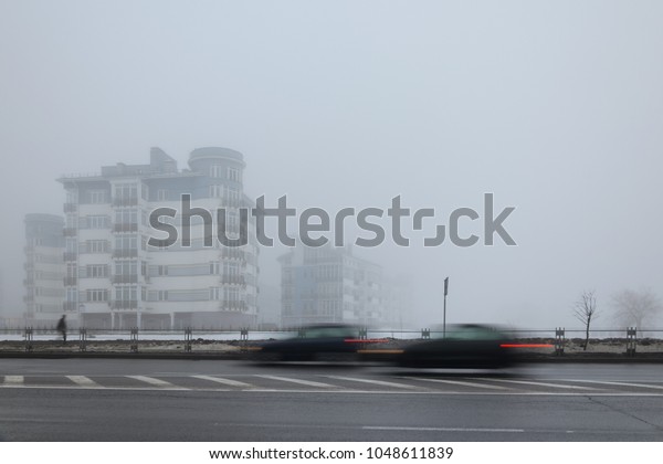 Mystical landscape of residential low-rise houses in\
dense fog