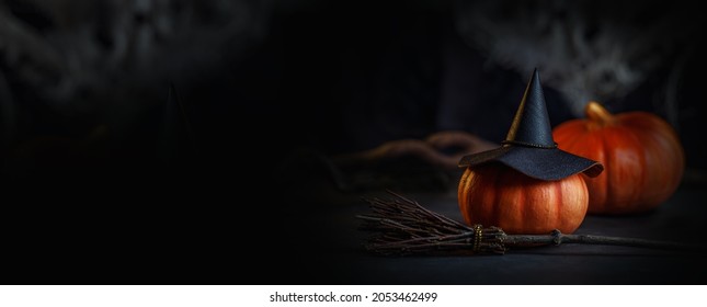 The mystical room of the witch. A decorative photo for Halloween with a hat, pumpkins and a broom. Banner in black and orange colors close-up.