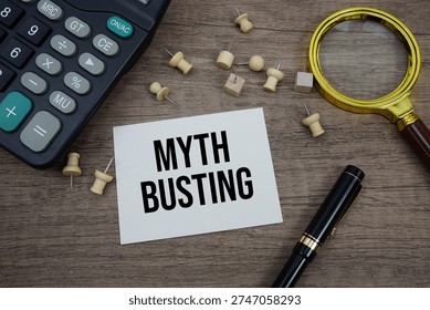 Myth Busting text written on notepad with pen, magnifying glass and calculator on wooden background