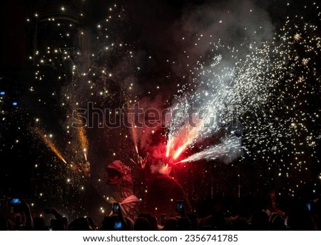 Mythical dragon dancing in a pyrotechnic show with fireworks shooting from its head during the traditional festival. People record with their mobile phones.