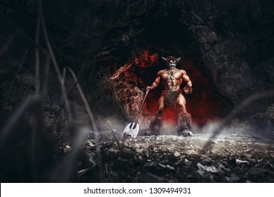 mythological minotaur  half bull half man stands in a rock cave in an aggressive stance. A monster of ancient Greek myth angry with axe in cave.