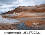 Myvatn Iceland, view across Namafjall or Hverir geothermal area with colorful barren hills, mud cauldrons, steaming vents and fumaroles, and the ever-present smell of sulphur