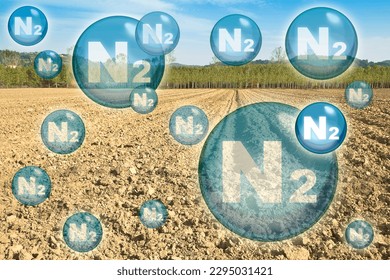 N2 nitrogen gas is the main constituent of the earth's atmosphere - concept with nitrogen molecules against a plowed field