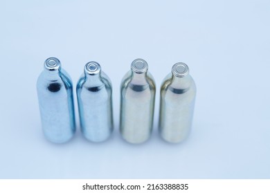 N2O Nitrous Oxide Cream Charger Or Soda CO2 Cattridge Compressed Gas. Whipped Cream Charger Cartrige. Isolated On White Background. Or Laughing Gas Used With Balloon Drug Party.