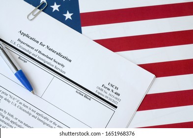 N-400 Application for Naturalization blank form lies on United States flag with blue pen from Department of Homeland Security - Shutterstock ID 1651968376