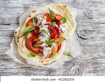 Naan bread and chicken vegetables stir fry on a  light wood rustic background. Delicious food