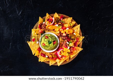Nacho chips with chili con carne, cheese sauce, and guacamole