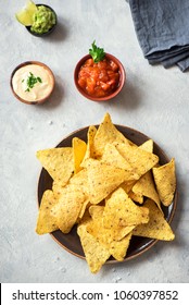 Nachos chips and assorted dip sauces. Tortilla corn nachos chips with salsa, melted cheese and guacamole, mexican snacks.