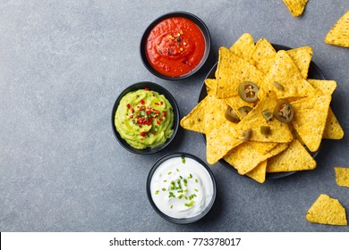 Nachos chips on a plate with sauces, dip variety. Grey stone background. Top view. Copy space. - Powered by Shutterstock