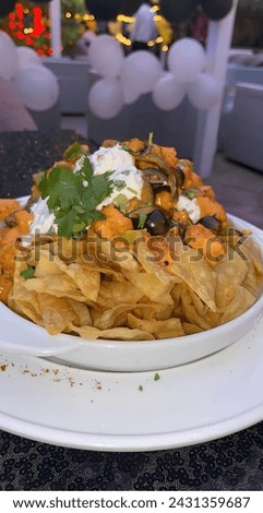 Nachos chips topped with jalapeños , cheese , meats, vegetables and sour cream