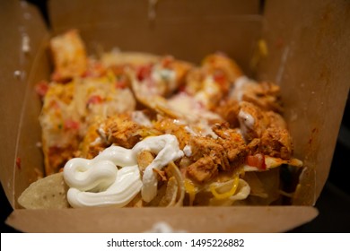 Nachos Covered In Shredded Chicken, Tomato, Green Chilis, Cheddar Cheese, And Sour Cream