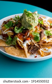 Nachos. Crispy tortilla chips topped with melted cheddar cheese, salsa, black beans, jalapenos, guacamole, sour cream and lettuce. Tex-Mex or Mexican restaurant classic traditional menu item. 