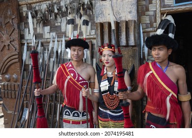 Naga tribesmen and a Naga women dressed in traditional attire with traditional weapons at Kohima Nagaland India on 1 December 2016