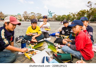 NAGASAKI, JAPAN - OCTOBER 2006: Japanese Kids Having Picnic Lunch In Box (called Bento), On The Square Of Nagasaki Peace Park