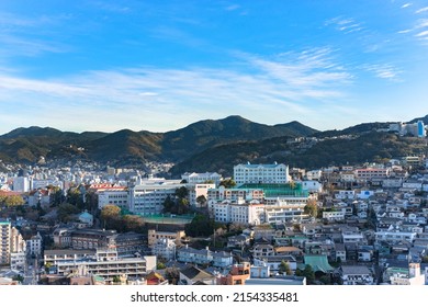 nagasaki, kyushu - december 13 2021: Bird's-eye view from Glover Garden of the Kaisei Junior and Senior High School complex surrounded by houses on the side of mount Hiko san and Hokazan in background