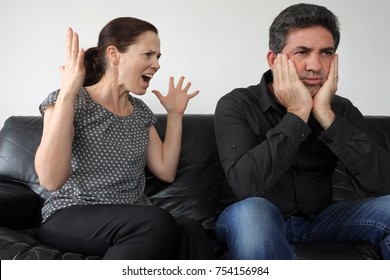 Nagging Wife (age 30) Complains And Shouting At Her  Upset Husband (age 40) At Home. Couple Relationship And Lifestyle Concept.  Real People. Copy Space