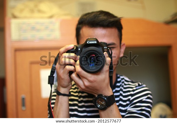 nagoya, august 16 2017: a man holding a black\
canon eos 80 d dslr\
camera