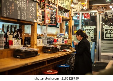 NAGOYA, JAPAN - DEC 11, 2018: Unidentified woman dining in small Izakaya restaurant in Japanese bar style