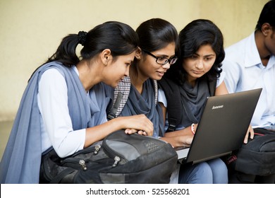 NAGPUR, MAHARASHTRA, INDIA, 9 APRIL 2016 : unidentified young students Surfing the net outdoors and working on laptop and smiling while sitting together on the outdoors staircase at campus.
