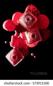 Nail art and beauty concept with trendy metallic red lacquer or nail polish spilled artistically around three square open bottles over a black background, top view with copy space