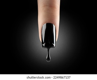 Nail art. Black gel polish dripping from beautiful long nail over black background. Woman finger with dark manicure and drop of nail polish. Fashion art design