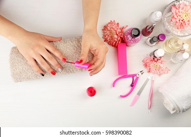 Nail Art Concept. Woman Giving Herself Manicure On White Table