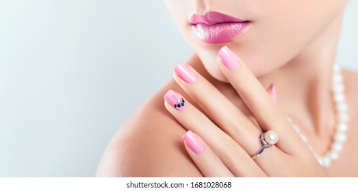 Nail art and design. Beautiful woman wearing make-up and pearl jewellery showing pink manicure with gems. Beauty fashion model. Skin care. Banner - Powered by Shutterstock