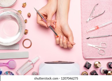 Nail care. beautiful women hands making nails painted with pink gentle nail polish on a pink background. Women's hands near a set of professional manicure tools. Beauty care