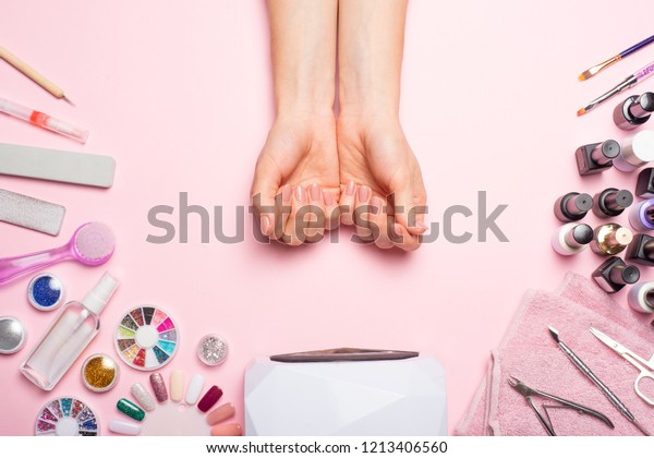 Nail care.\
beautiful women hands making nails painted with pink gentle nail\
polish on a pink background. Women\'s hands near a set of\
professional manicure tools. Beauty\
care