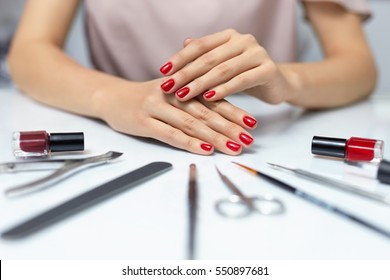 Nail Care. Closeup Of Beautiful Woman Hands Showing Perfect Nails Painted With Red Nail Polish On White Background. Female Hands Near Set Of Professional Manicure Tools. Beauty Care. High Resolution