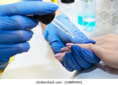 Nail care. Manicure in the salon. Applying oil on nails in the salon. The master manicures the girl, beauty and health. Manicure process. Master in mask and gloves. - Shutterstock ID 1548894041