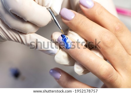 Nail design. The process of coating the nails with gel polish and drawing the design with a brush by a specialist in a beauty salon. Close-up. Space for text