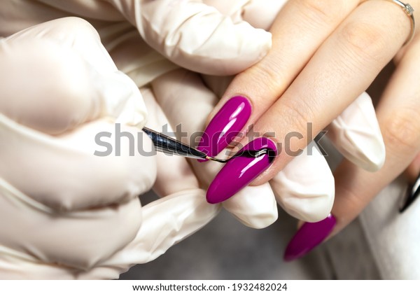 Nail design of a young\
girl is drawn by a manicure master with a thin brush in a beauty\
salon. Close-up