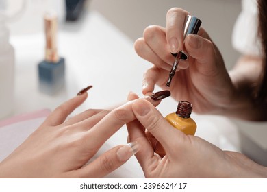 Nail designer applies nail polish to customers