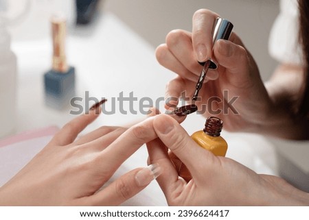 Nail designer applies nail polish to customers
