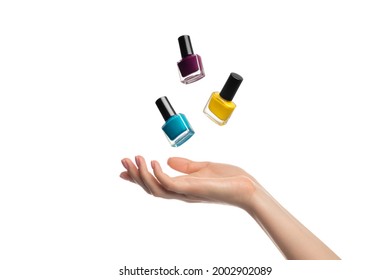 Nail polish bottles levitate, flying over a woman's hand - Shutterstock ID 2002902089