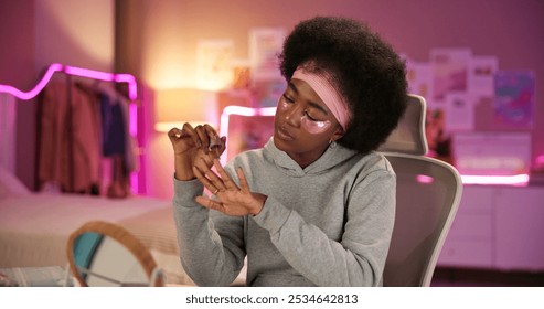 Nail polish, self care and relax with black woman in bedroom for beauty routine, manicure and eye mask. Cosmetics, collagen and product with person at home for diy facial, detox and dermatology - Powered by Shutterstock