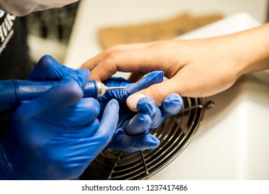 Nail Tech Filing Nails With Nail File. Professional Manicure Tools. Blue Gloves On The Hands Of The Master