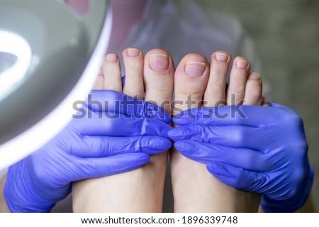 The nail technician examines the feet after processing. Medical pedicure in the salon.