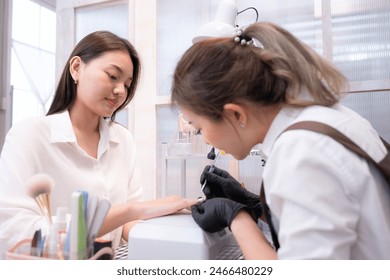 A nail technician is painting the nails of a customer. - Powered by Shutterstock