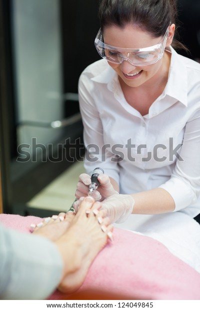 Nail\
technician removing callus at feet in nail\
salon